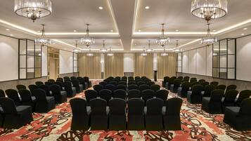 A conference room with rows of chairs, chandeliers, and a patterned carpet.