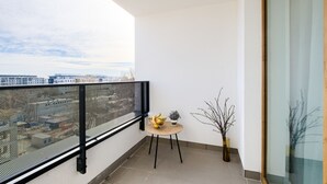 Un balcón con una mesa redonda, una pequeña maceta y un jarrón decorativo.