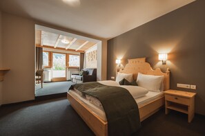 Een slaapkamer met een houten bed, nachtkastjes en uitzicht op een balkon.