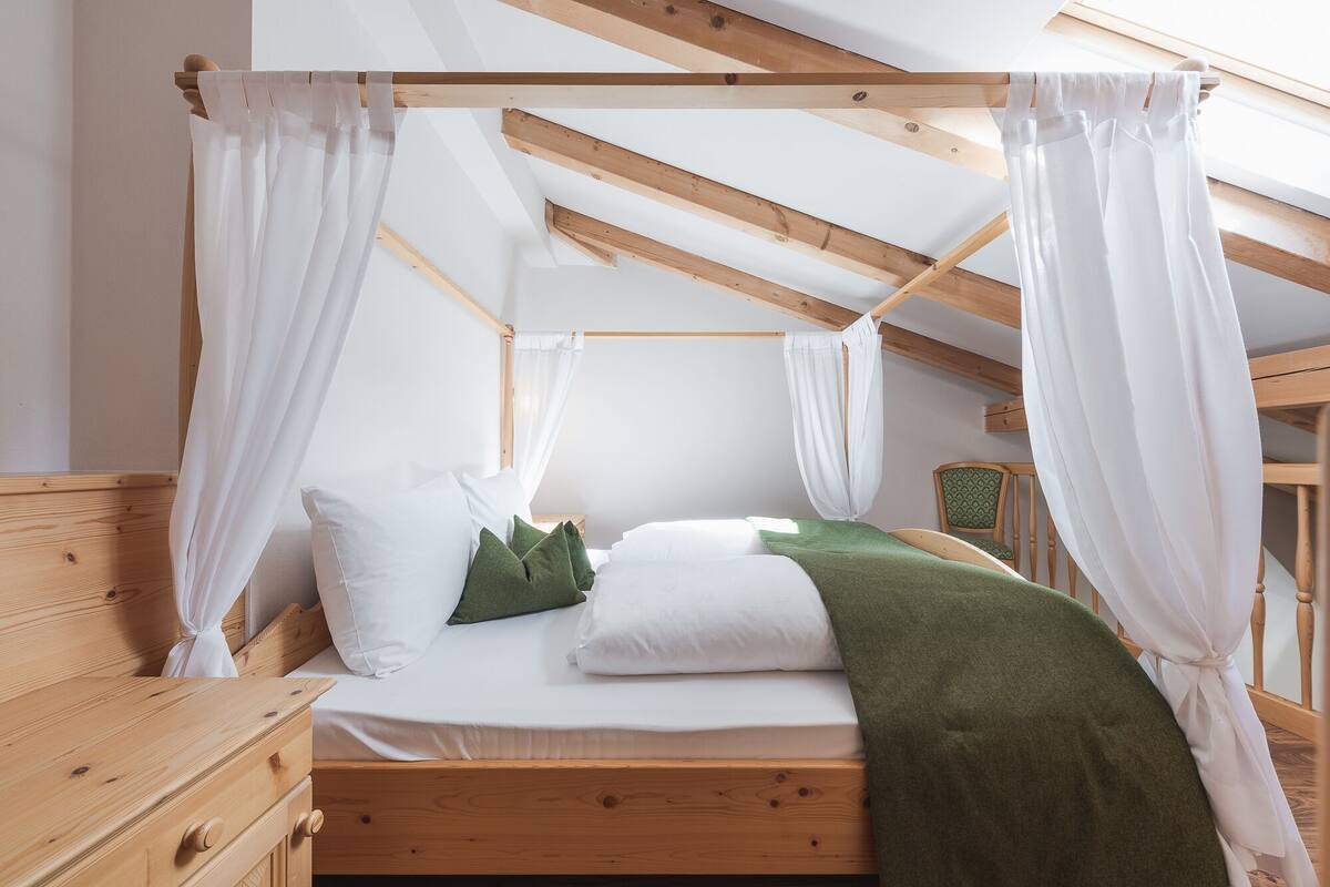 A bed with a wooden frame, white bedding, and green pillows.