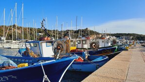 A marina with several small boats docked, a yellow buoy, and a rocky hillside in the background. - Le Villette di Ruoni (Santa Teresa di Gallura)