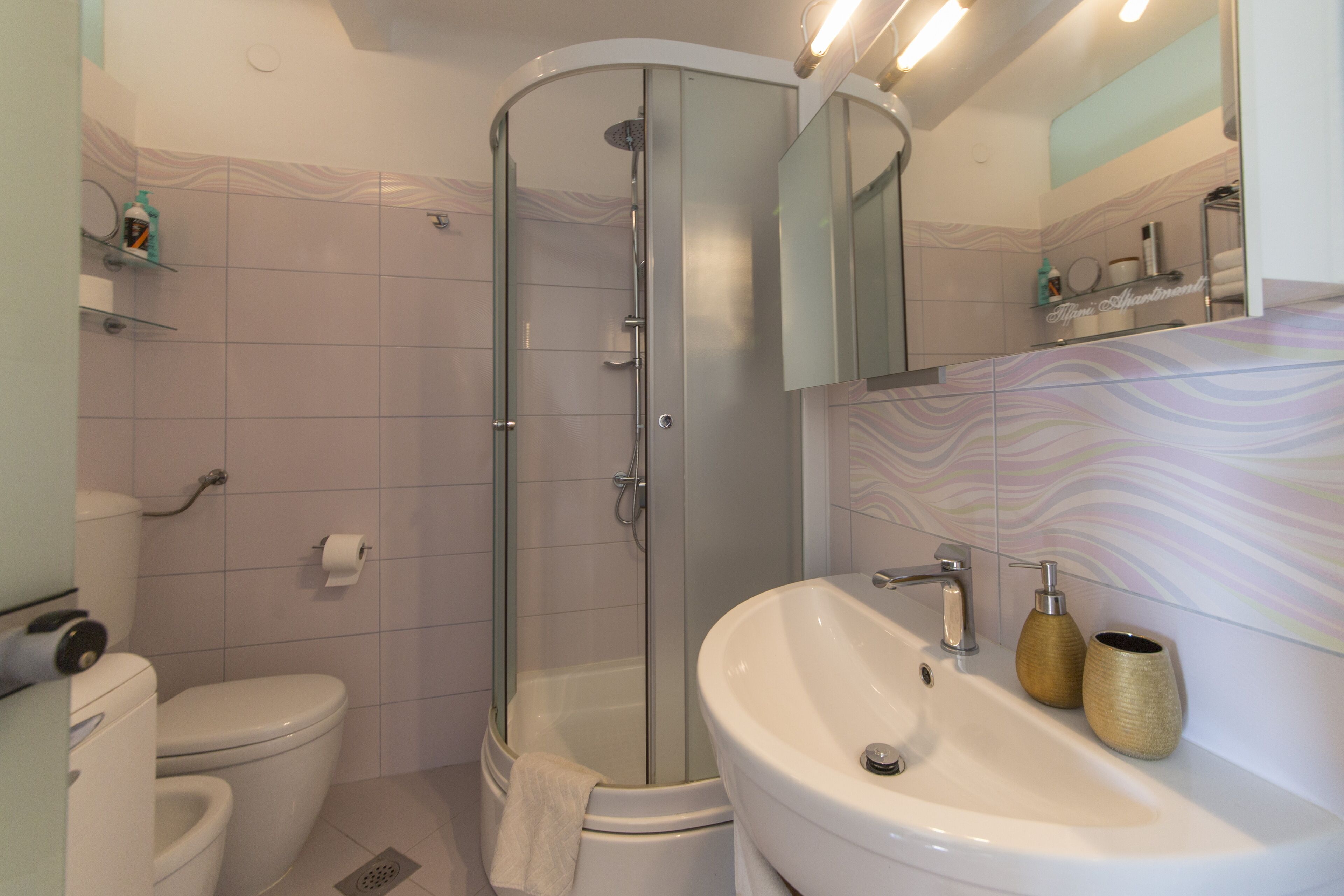 A modern bathroom with a glass-enclosed shower, a white sink, and a toilet.
