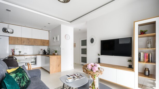 A modern living room with a grey sofa, a coffee table, and a TV on the wall. - M&R Apartament Airport&Business DeLuxe Cybernetyki (Warsaw)