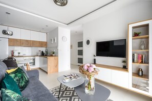 Una sala de estar moderna con un sofá gris, una mesa de centro y un televisor en la pared.