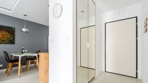 A modern room with a dining area, a large mirror, and a door. - M&R Apartament Airport&Business DeLuxe Cybernetyki (Warsaw)
