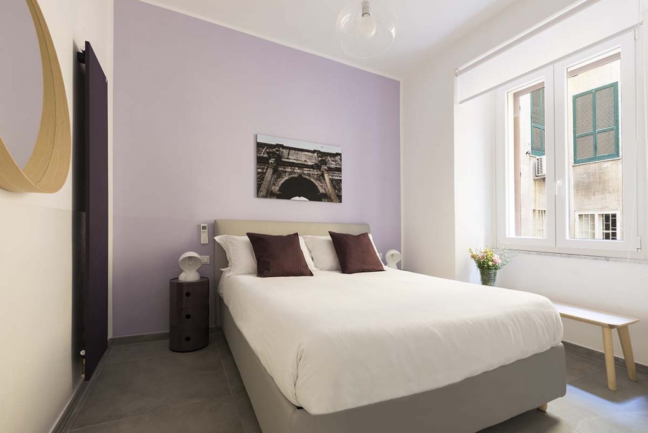 Une chambre à coucher avec un lit, un tableau accroché au mur, une table de chevet et une fenêtre avec des volets.