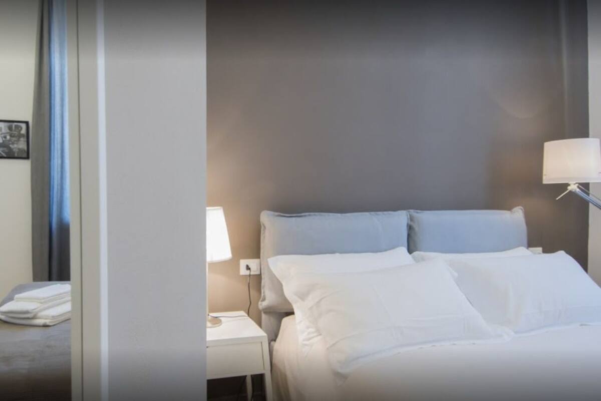 Een hotelkamer met een bed, een nachtkastje, een lamp en twee ingelijste foto's aan de muur.