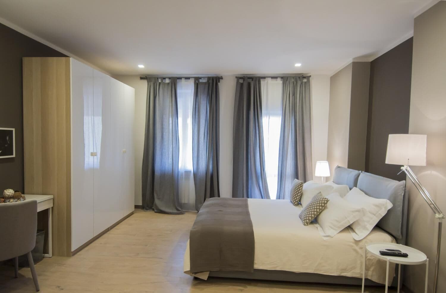 Een moderne hotelkamer met een groot bed, nachtlampjes, een bureau en een stoel.