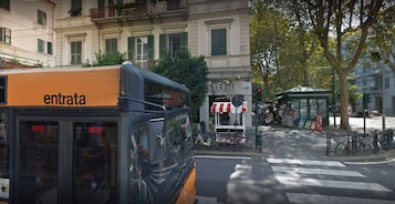Un autobús con la leyenda "entrata" en una parada de autobús, con un edificio al fondo.