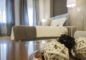 Una habitación de hotel moderna con una cama bien hecha, una mesita de vidrio con adornos y vistas a la ciudad desde la ventana.