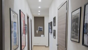 Un pasillo con cuadros en las paredes, una puerta a la derecha y un interruptor de luz a la izquierda.