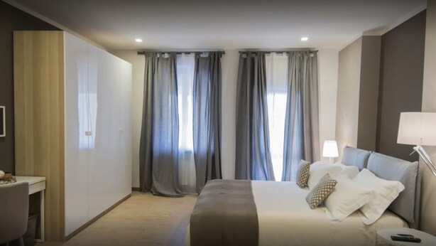 Una habitación de hotel con cama, lámparas de noche, escritorio y cortinas.
