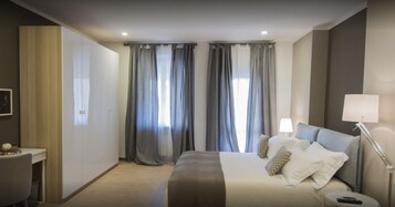 Una habitación de hotel con cama, lámparas de noche, escritorio y cortinas.