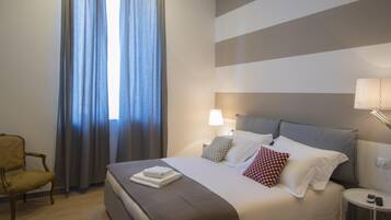 A hotel room with a bed, a chair, and curtains.