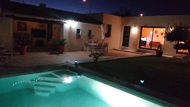 A swimming pool with steps leading into it, surrounded by a patio area with outdoor furniture and potted plants. - Contemporary villa at the door of the luberon (morieres les avignon)