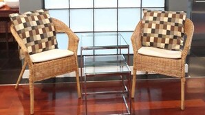 Two wicker chairs with checkered cushions, a glass table, and a large window with a grid pattern.