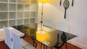 A modern dining area with a glass table, white chairs, a lamp, and wall-mounted mirrors.