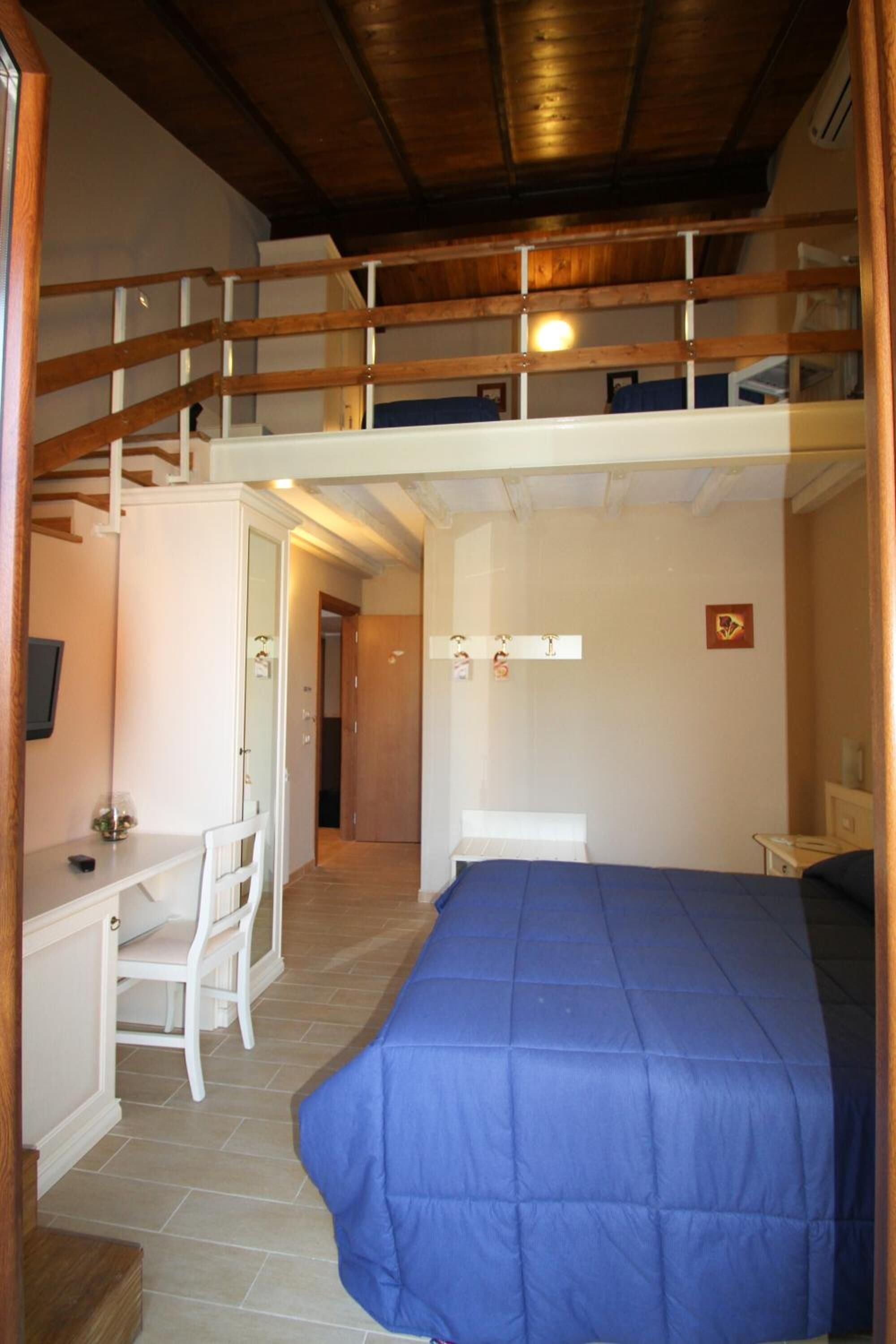 Una stanza con un letto a castello, una scrivania con sedia e un letto con copriletto blu.
