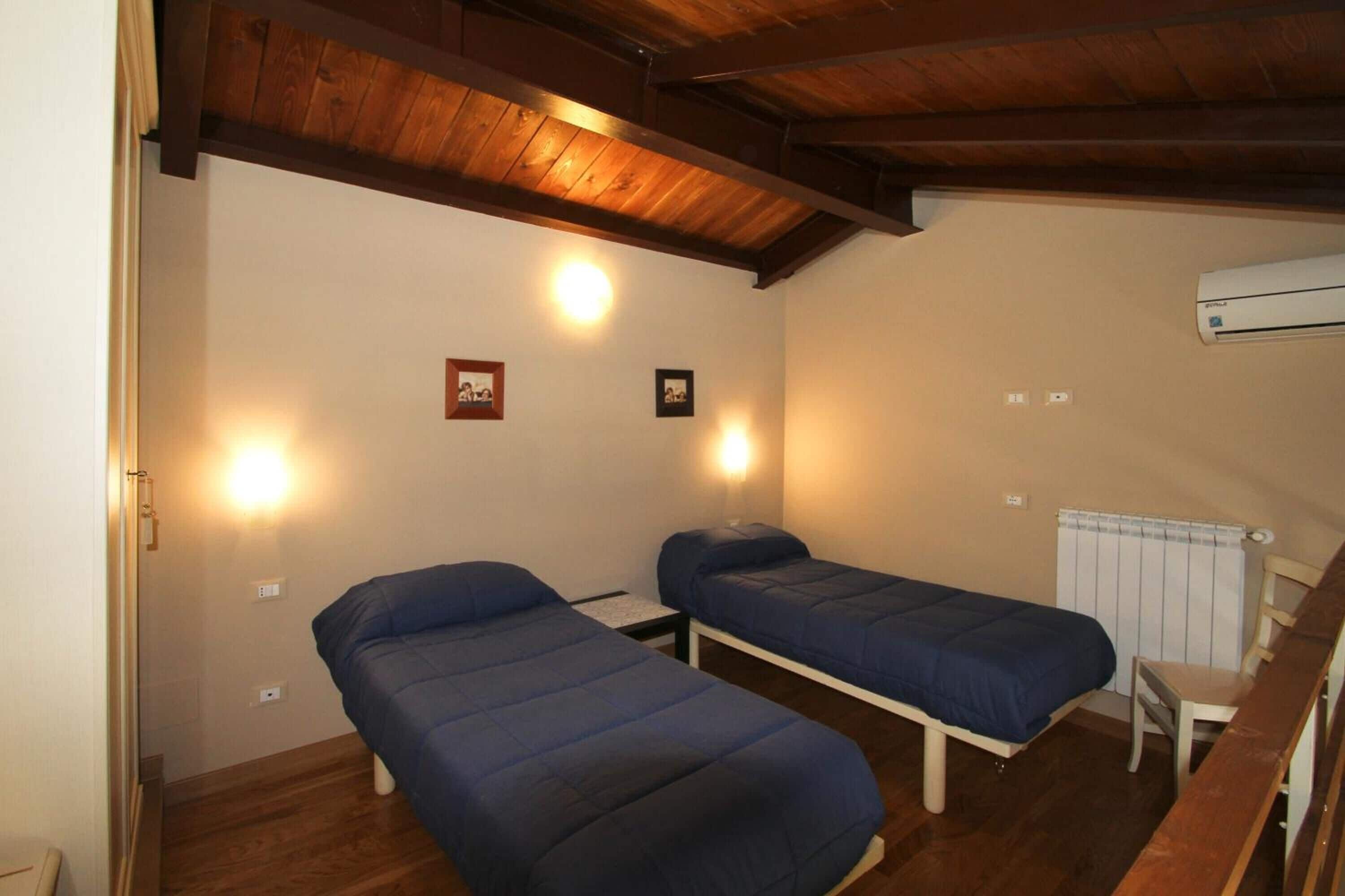 Een kleine, knusse kamer met twee eenpersoonsbedden, een houten plafond en een radiator.