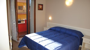 A bedroom with a large bed, a bedside table, a nightstand, and a door leading to a balcony. - La Chioccia (Valmontone)