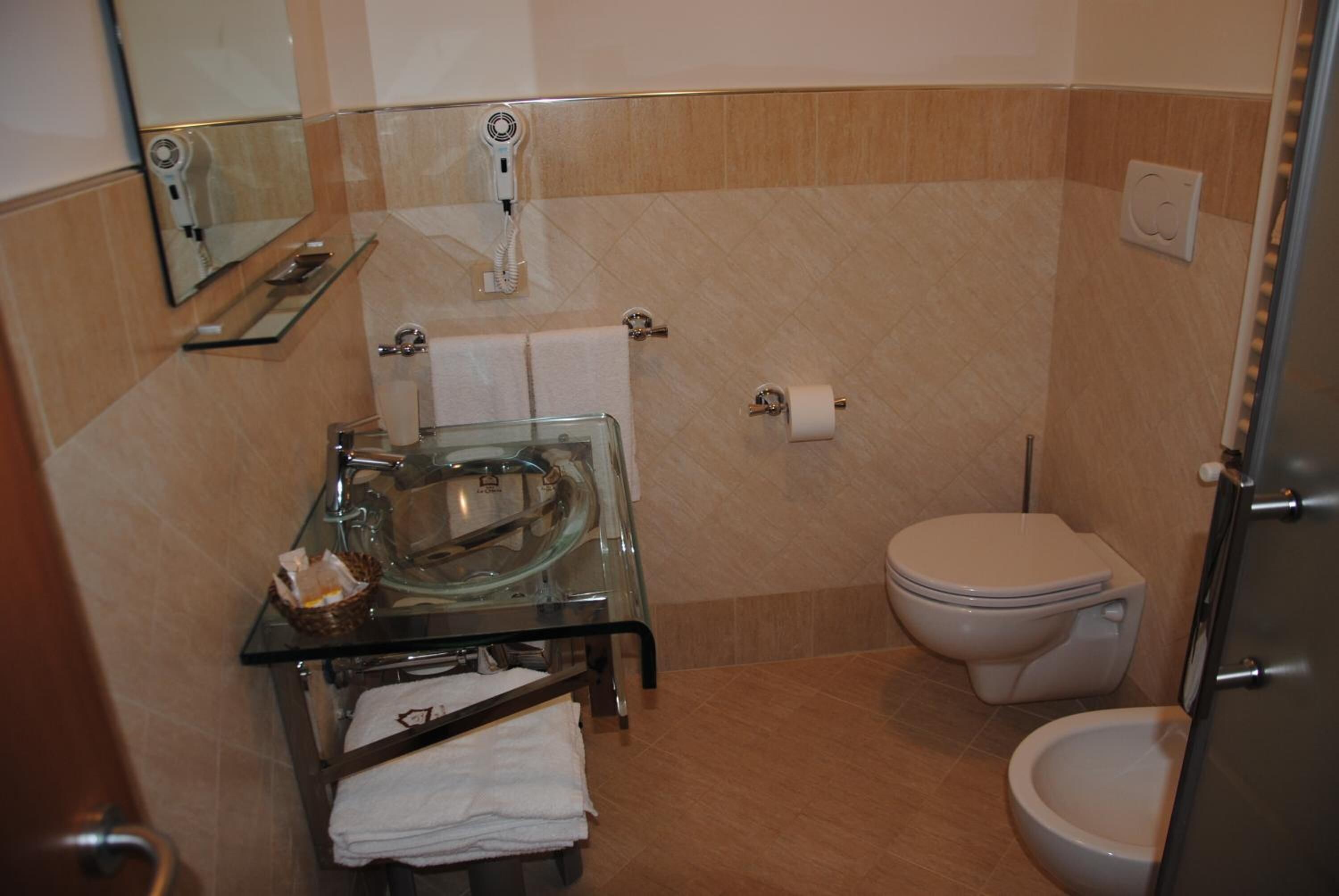 A modern bathroom with a glass sink, a toilet, and a shower.