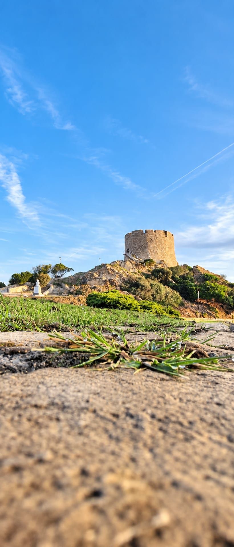 A historical stone tower on a hill with a clear sky.