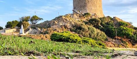 A historical stone tower on a hill with a clear sky.