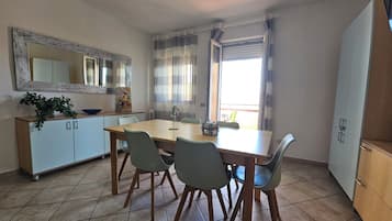 Uma sala de jantar com uma mesa de madeira, quatro cadeiras, um armário e um espelho.
