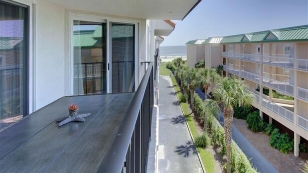 Ein Balkon mit einer Meerstern-Dekoration, Blick auf ein Gebäude mit Gründach und ein mit Pflanzen gesäumter Weg.