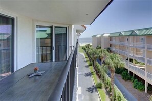 Un balcon orné d’une étoile de mer, une vue sur un immeuble doté d’un toit végétalisé et un sentier bordé de plantes.