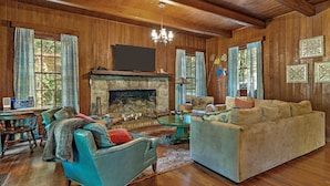 A cozy living room with a stone fireplace, wooden walls, and a large sofa.