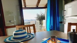 A dining area with a table, chairs, a hat, a coffee cup, and a view of the outdoors. - Villette Panoramiche Filetta (Santa Teresa di Gallura)
