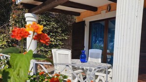 An outdoor patio with white chairs and a table, surrounded by greenery and flowers. - Villette Panoramiche Filetta (Santa Teresa di Gallura)