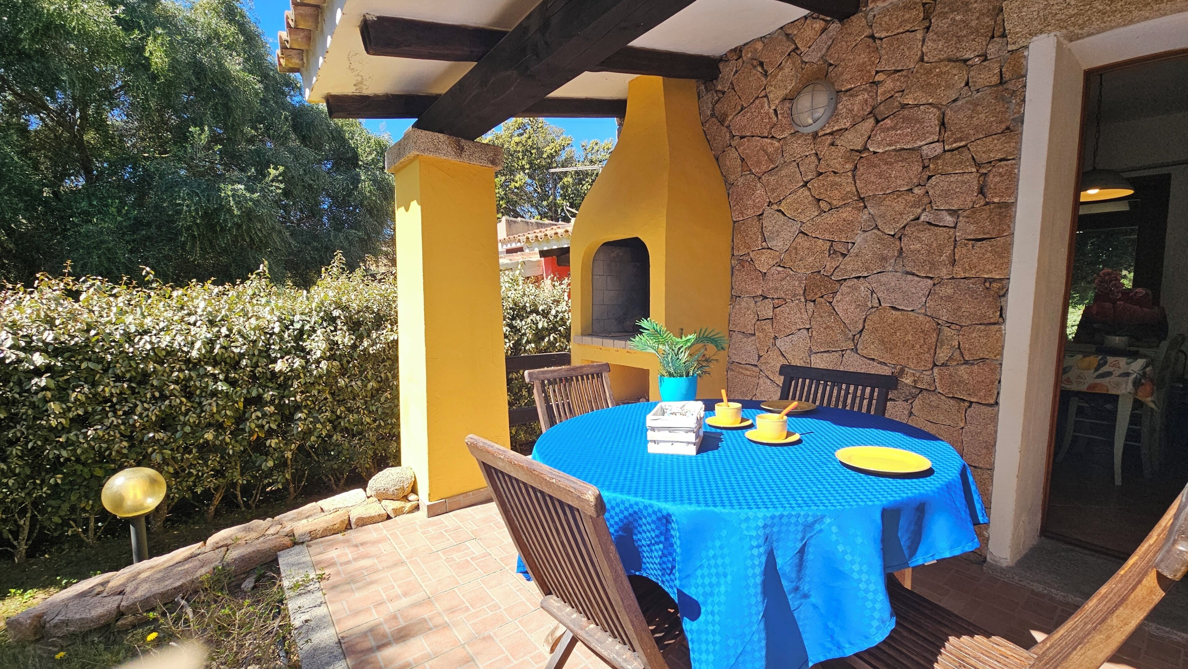 Eine Terrasse im Freien mit einem runden Tisch, Stühlen und einer Steinmauer.