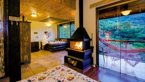 Una habitación acogedora con chimenea, zona de comedor y un gran ventanal con vistas a zonas verdes.