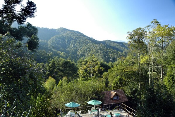 Vista de un paisaje montañoso con un edificio pequeño y mesas al aire libre, con sombrillas.