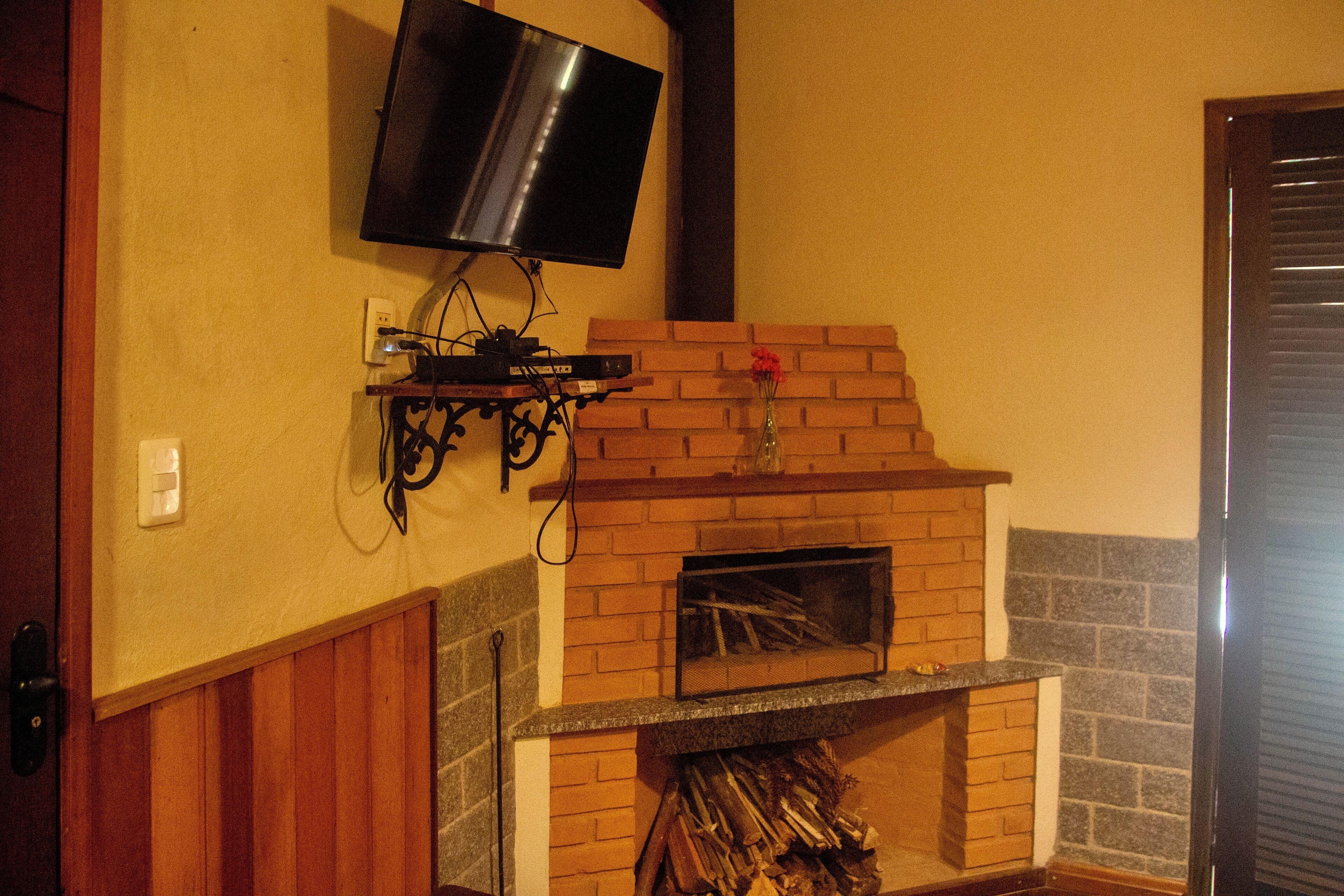 A fireplace with a TV mounted above it, a brick wall, and a wooden door.