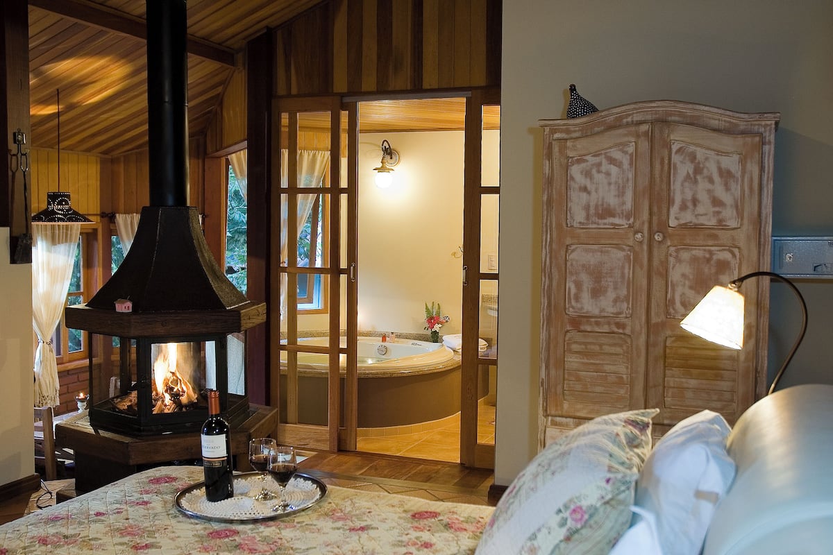 Um quarto com lareira a lenha, banheira e armário de madeira.