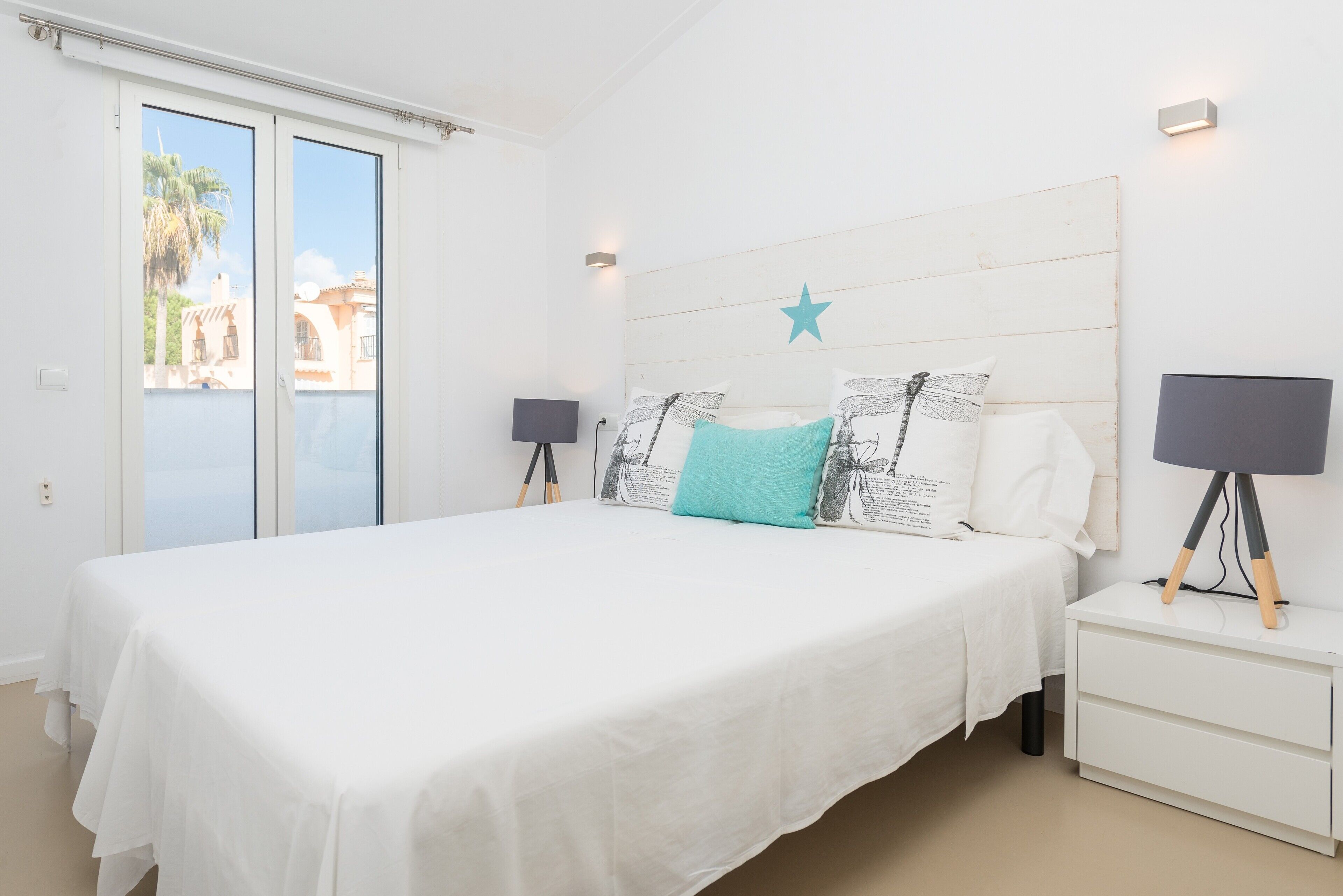 A bedroom with a large bed, a nightstand with a lamp, and a star decoration on the headboard.