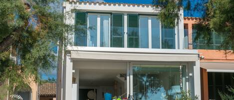 Una casa moderna de dos pisos con un porche cubierto, ventanas amplias y vistas del entorno.