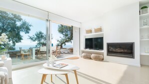 A modern living room with a large glass door leading to a balcony with a view of the sea. - PORT NOU CA NA CATI - Chalet with sea views in Cala Bona. Free WiFi (Son Servera)