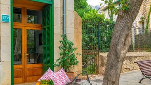 A stone-paved entrance with a wooden door and green shutters, a bicycle, and a bench. - CA SA TIA (SÓLLER) - Townhouse with nice patio in the centre of Sóller. Free WiFi (Sóller)