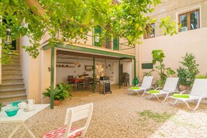 Eine Terrassensitzgruppe im Freien mit Essbereich, Sitzmöbeln und einem Hauseingang.