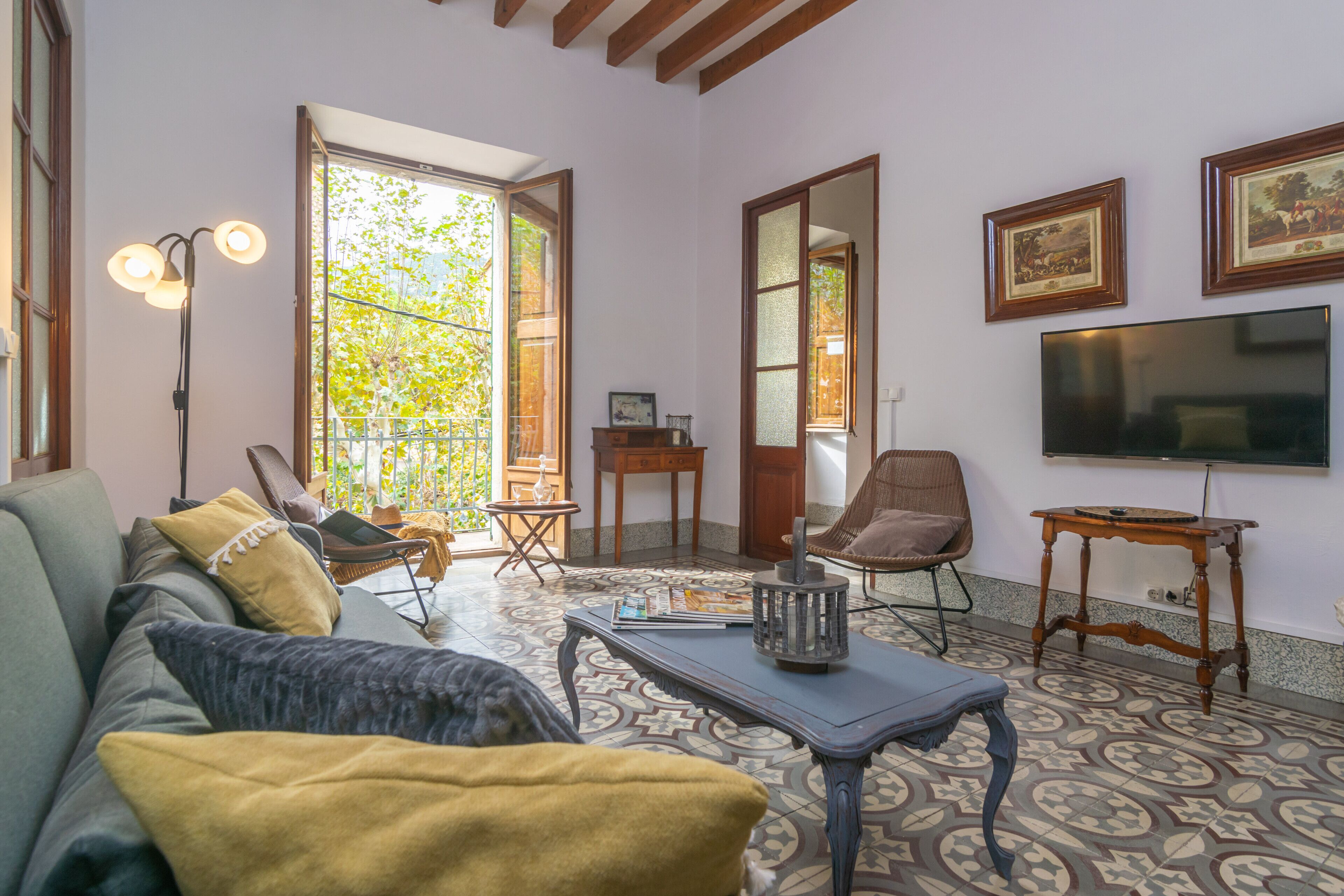 Una sala de estar con un sofá, sillones, una mesa de centro y un televisor. Hay un ventanal con vistas a zonas verdes.