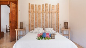 A neatly made bed with a white duvet, two pillows, and a bedside table with a lamp and a small plant. - CA SA TIA (SÓLLER) - Townhouse with nice patio in the centre of Sóller. Free WiFi (Sóller)