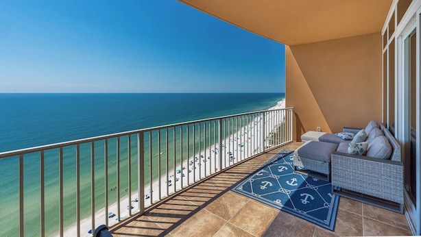 A balcony with a view of the beach and ocean.