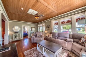A spacious living room with a wooden ceiling, large windows, and a fireplace.