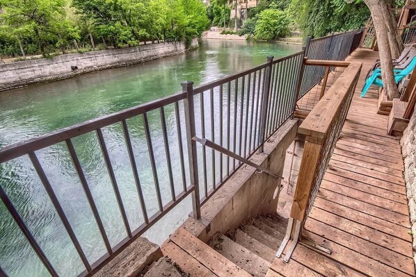 A wooden deck with a metal railing overlooking a river.