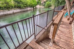 Une terrasse en bois avec une rambarde en métal donnant sur une rivière.