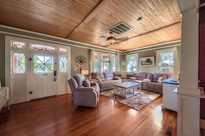 Un salon spacieux doté d’un plancher en bois, d’un ventilateur de plafond et d’un grand canapé d’angle.